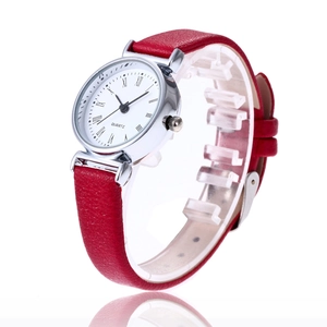Macro detail of quartz watch featuring Roman numeral dial and red leather strap