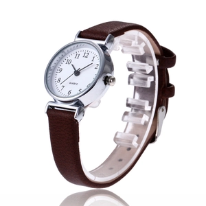 Detail view of the brown leather strap and silver quartz watch with Arabic numerals