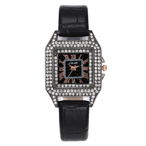 Detail of square crystal-encrusted bezel with Roman numerals on a black leather strap watch