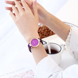 Montre élégante à cadran étoilé violet avec bracelet magnétique en or rose sur fond blanc
