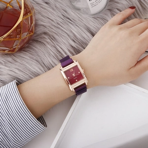 Nahaufnahme der eleganten quadratischen Roségolduhr mit lila Netzband am Handgelenk