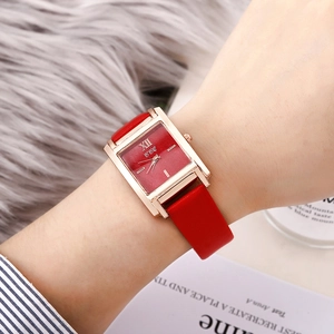 Gros plan d'une montre rectangulaire or rose pour femme avec cadran rouge et cuir