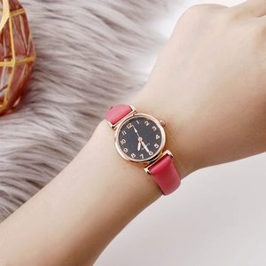 Close-up of pink leather strap watch with starry black dial worn on a female wrist
