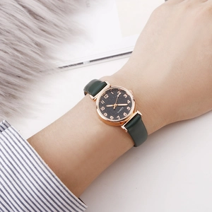 Close-up of minimalist rose gold quartz watch with starry dial and green leather strap