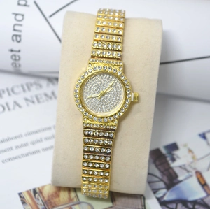 Detail of a luxury gold women's watch featuring a full crystal paved dial and metal band