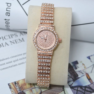 Close-up of rose gold watch with full diamond setting on a soft beige velvet pillow