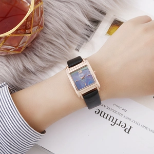 Détail d'une montre carrée or rose pour femme avec bracelet en cuir noir au poignet