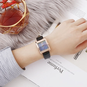 Photo au poignet d'une montre quartz rectangulaire en or rose pour femme avec bracelet cuir