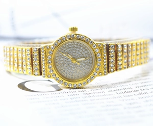 Close-up of gold-plated women's watch with crystals on dial and steel strap