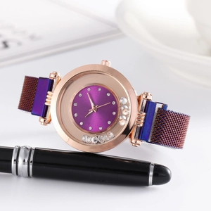 Gros plan sur montre or rose avec cadran violet et strass mobiles sur bracelet en maille