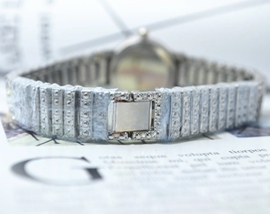 Close-up of silver diamond watch steel strap with studs and protective film details
