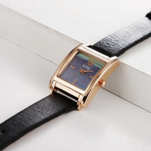 Vue rapprochée d'une montre rectangulaire dorée avec cadran nacré bleu et bracelet en cuir