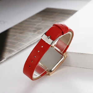 Détail du bracelet en cuir rouge et boucle dorée d'une montre à quartz carrée