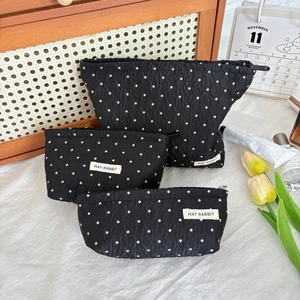 Detailed close-up of three black polka dot cosmetic bags in different sizes for travel