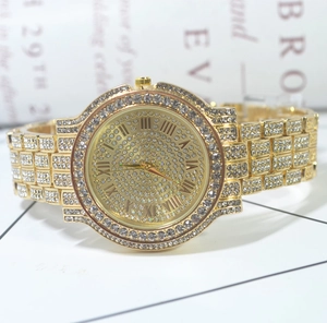 Macro detail of gold-tone watch with full crystal pavé setting and Roman numerals