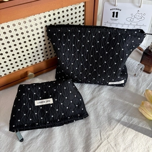 Detail of black polka dot cosmetic bags with pleated fabric texture and zipper closure