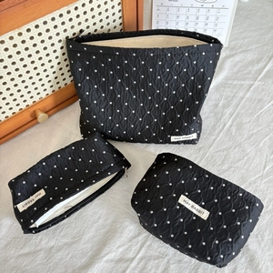 Detailed macro view of three different sized black polka dot cosmetic pouches with zip closure