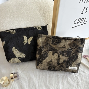 Detail of black butterfly cosmetic bags with gold embroidery and May Rabbit brand label