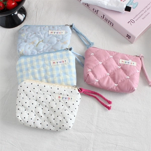Detailed view of quilted cotton mini pouches with zipper pulls and side brand labels