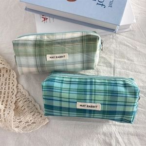 Detail of plaid fabric pencil cases with metal zippers and brand labels in various colors