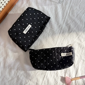 Close-up of black quilted makeup bags with white polka dots and May Rabbit label