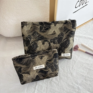 Detail of premium black makeup bags featuring golden 3D butterfly jacquard patterns
