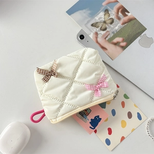 Close-up of quilted cosmetic bag with bows on desk next to laptop and accessories