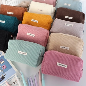 Detailed pile of multi-color corduroy pouches showing soft ribbed texture and brand label