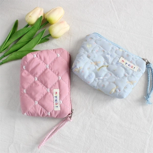 Detailed shot of quilted heart and cartoon lipstick bags with wrist straps and zippers