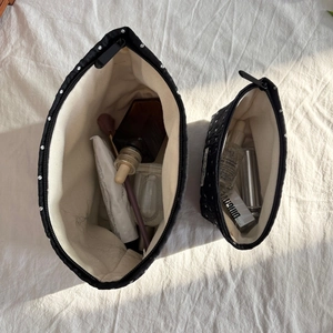Detail of black polka dot canvas makeup bags showing interior storage for skincare bottles