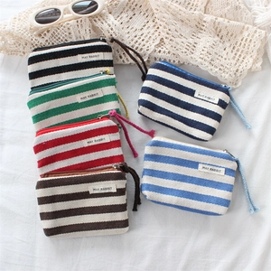 Detail showing colorful striped canvas coin purses with zipper closures and wrist straps