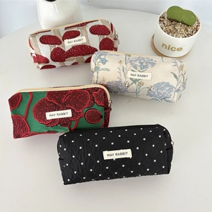 Détail de quatre trousses en tissu jacquard fleuri avec étiquette May Rabbit