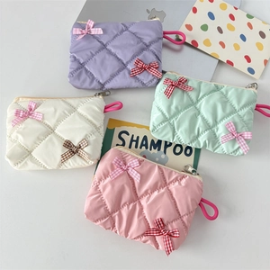Detailed view of quilted macaron cosmetic bags with bows and metallic zipper