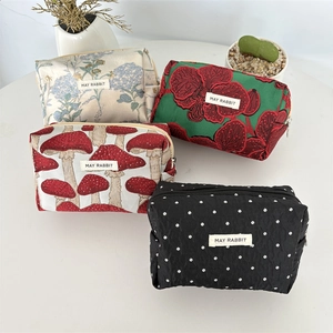 Trousses à fleurs et à pois et sacs à cosmétiques sur un bureau blanc et lumineux