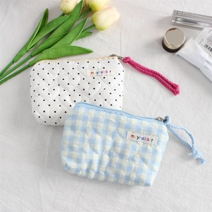 Detail of heart quilted cosmetic bags in polka dot and plaid patterns with zip closure