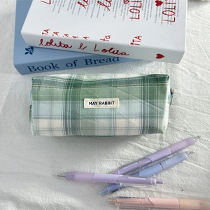 Detail of checkered pencil case with logo label and aesthetic stationery background