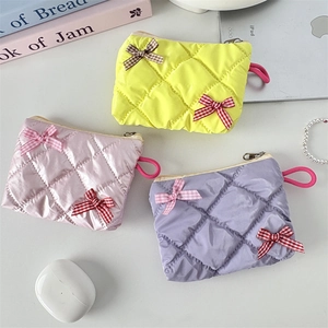 Detailed view of quilted bow makeup bags in yellow, pink and purple with grid ribbons
