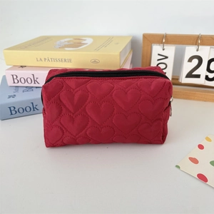 Detailed view of red heart-shaped quilted fabric and black zipper on a makeup bag