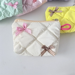 Quilted cosmetics pouch with pearl finish and fabric bows in diverse pastel colors