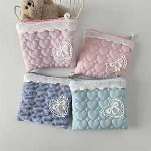 Detailed macro view of quilted lace pouches with heart patches and pearl zipper accents