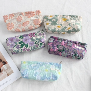 Flat lay of multiple floral embroidery mini canvas pouches on white wrinkled fabric