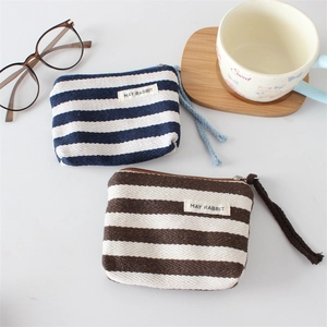 Close-up of striped canvas coin purses with woven lanyards and smooth zipper details