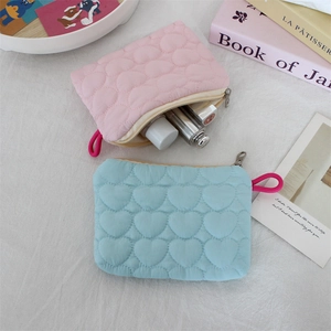 Detail of heart quilted cosmetic bags in pink and blue with metal zippers and wristlet