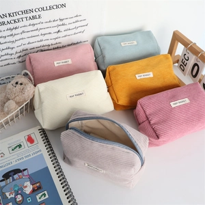Stack of colorful corduroy pouches in six pastel shades with a May Rabbit cloth label