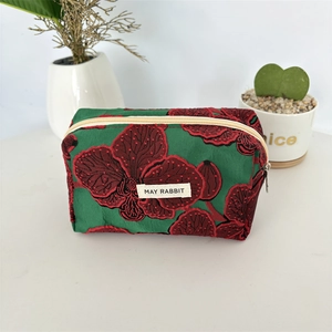 Détail de la pochette en jacquard vert avec motifs d'orchidées et étiquette MAY RABBIT