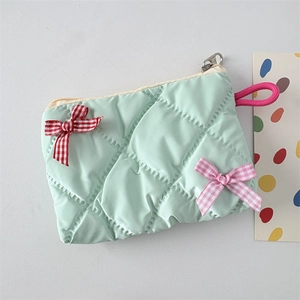 Detail of light green quilted cosmetic bag with plaid bows and metal zipper closure