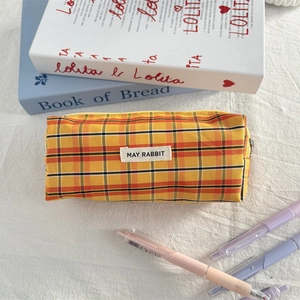 Detail of checkered orange pencil case with top zipper and woven May Rabbit label