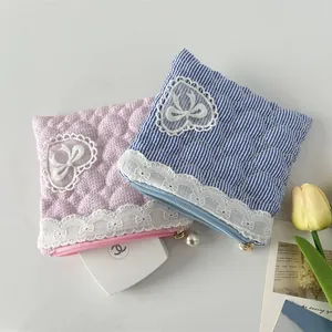 Detail of quilted lace pouch with heart embroidery and pearl zipper in pink and blue
