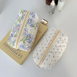 Close-up of quilted floral cosmetic bags with blue and purple patterns on a prop book
