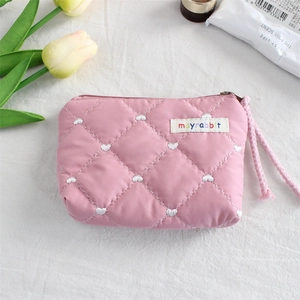 Detailed view of pink quilted storage bag featuring white heart embroidery and zipper